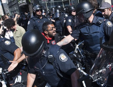 Activistas protestan en Toronto por la cumbre del G-20 ante un grupo de policías antidisturbios.